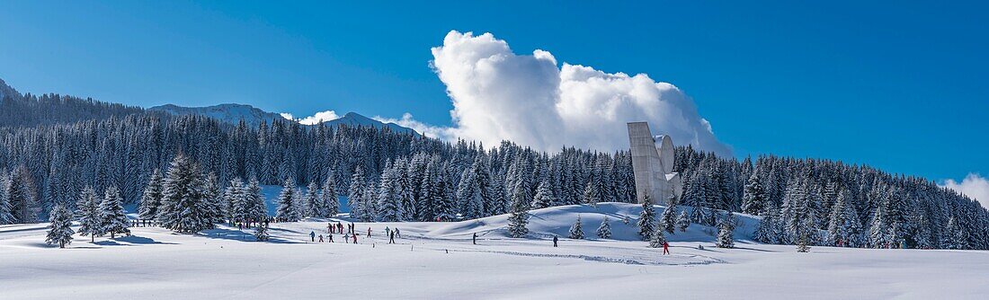 Frankreich,Haute Savoie,Bornes-Massiv,Plateau des Glieres,Panoramablick mit Kinder-Skating-Gruppe auf Langlaufloipen und dem Nationaldenkmal des Widerstands von Emile Gilioli