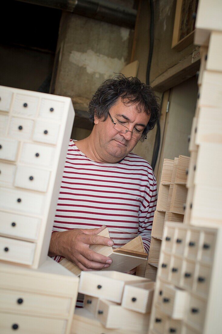 Frankreich,Jura,Lajoux,der Laienschreiner Bruno Marelle in seiner Werkstatt für Laienschreiner macht Möbel mit Schubladen