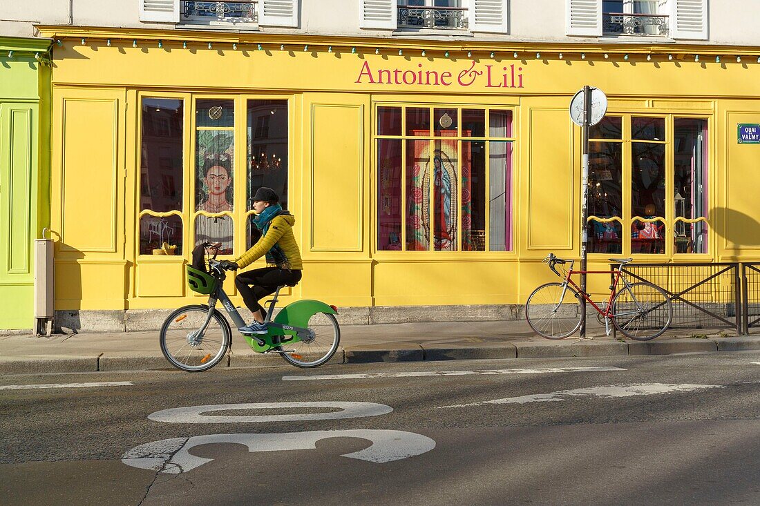 France,Paris,cyclist in front of Antoine et Lili shop window on Quai de Valmy along Saint Martin canal