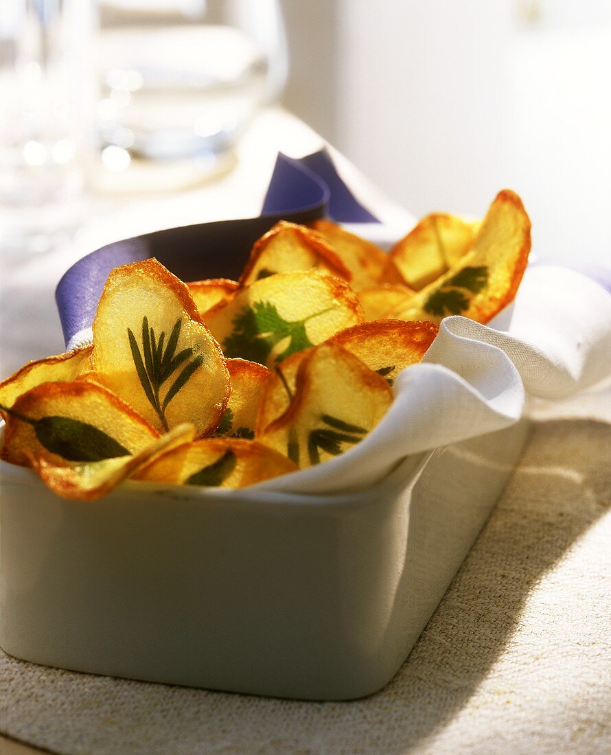 Potato & herb crisps on kitchen cloth in square dish