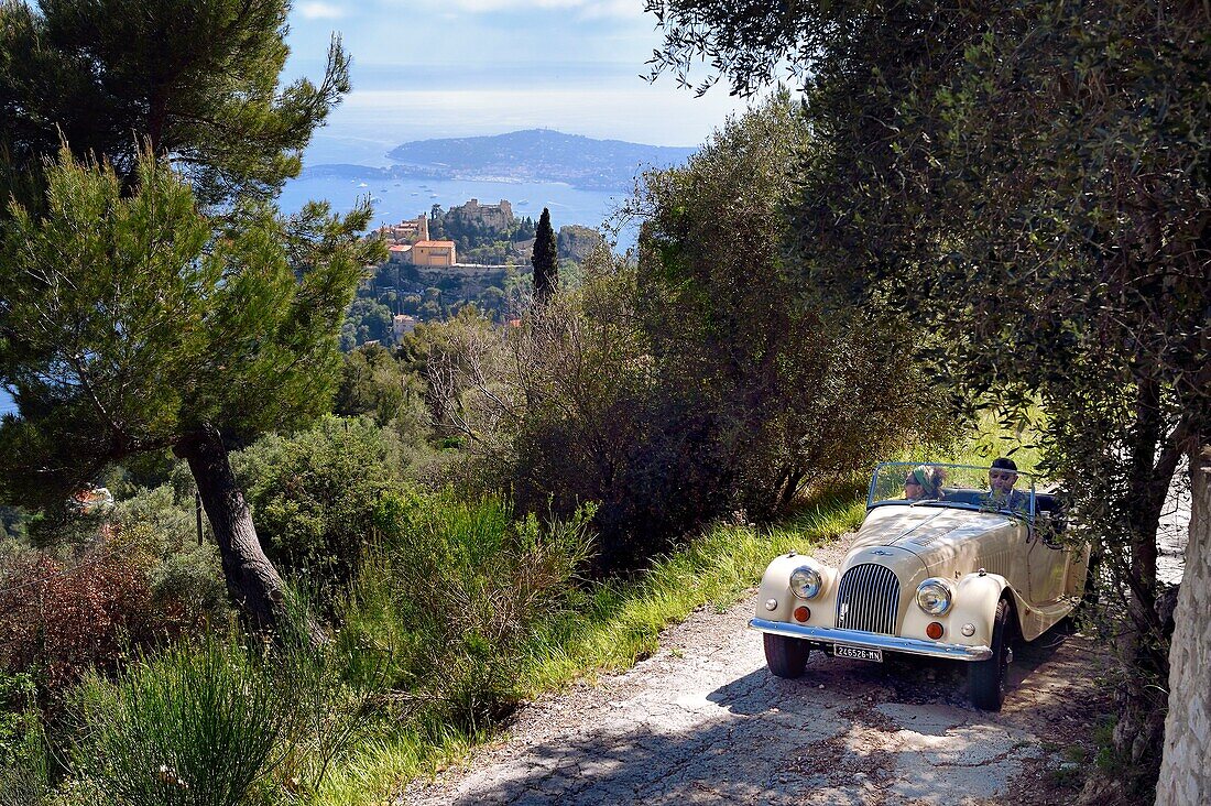 France,Alpes Maritimes,discovering the coast in a Morgan Roadster 4/4 vintage car,here on a road overlooking the hilltop village of Eze,Saint Jean Cap Ferrat in the background
