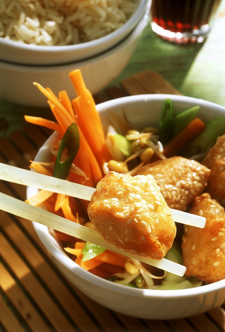 Chicken pieces with sesame(one on chopstick), vegetables