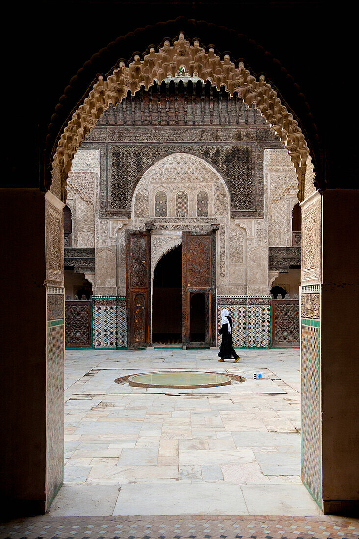 Morocco,Woman walking across courtyard of Medersa Bou Inania,Fez