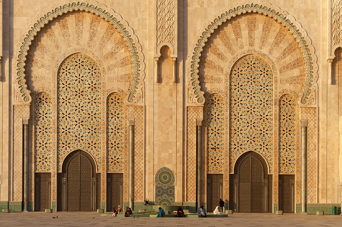 Morocco,People in front of massive doors to Hassan II Mosque at dusk,Casablanca