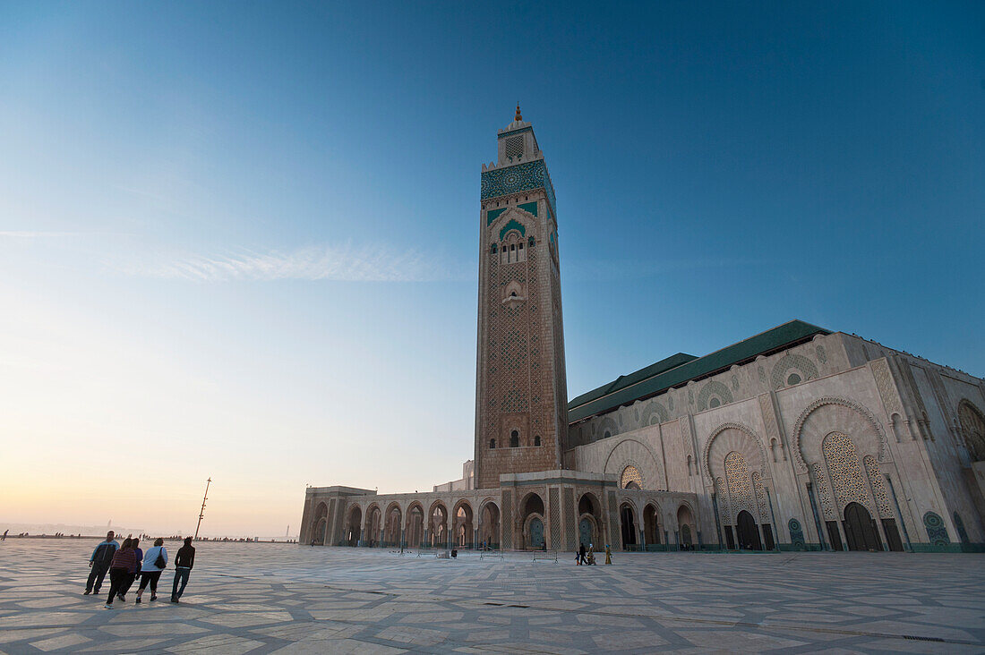 Marokko,Menschen gehen über den Hof vor der Hassan II Moschee in der Abenddämmerung,Casablanca