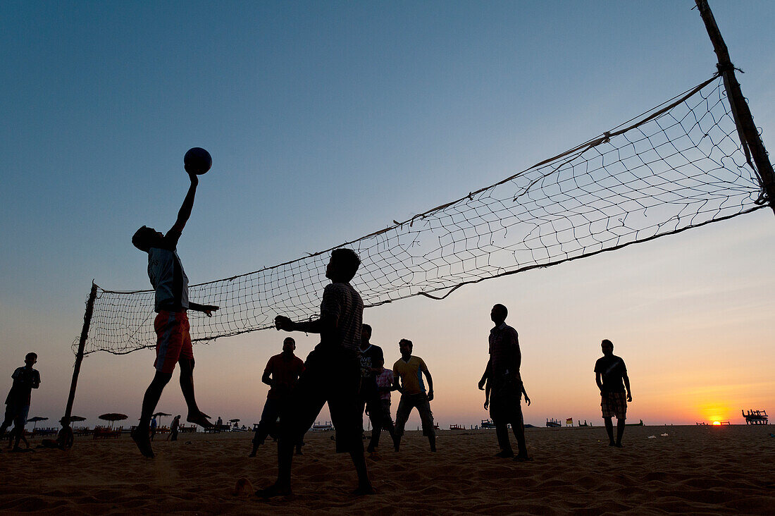 India,Men playing beach volleyball at dusk,Goa