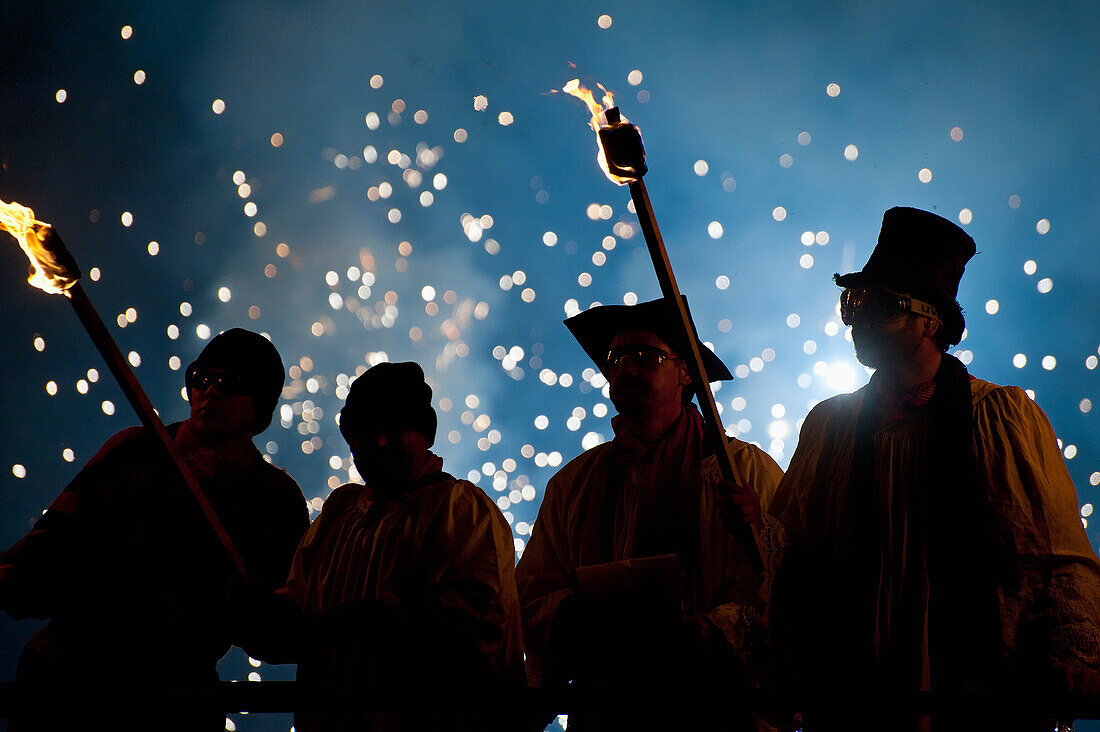 UK,England,People dressed as clergy on stand with fireworks behind them at Newick bonfire night,East Sussex