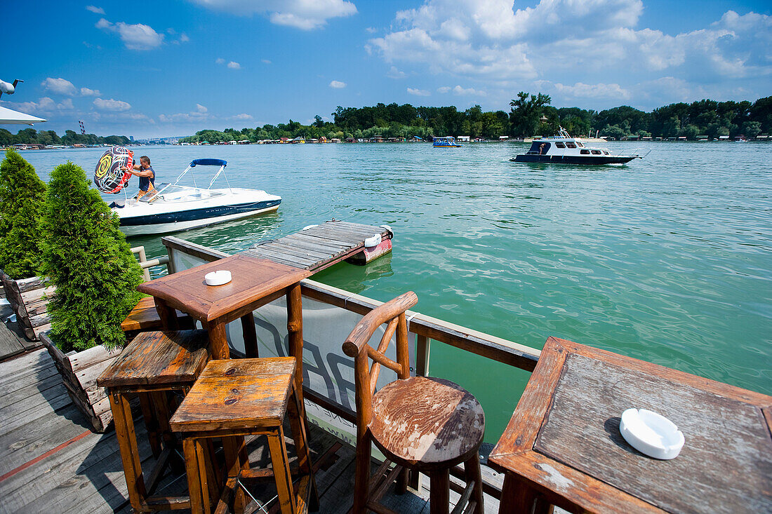 Serbia.,River Danube,Belgrade,floating on river,Small boat passing by. tables and chairs. Cafe Bars