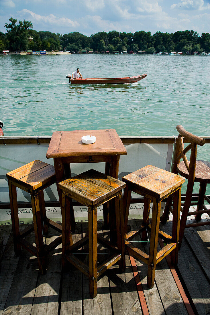 Serbia.,River Danube,Belgrade,floating on river,Small boat passing by. tables and chairs. Cafe Bars