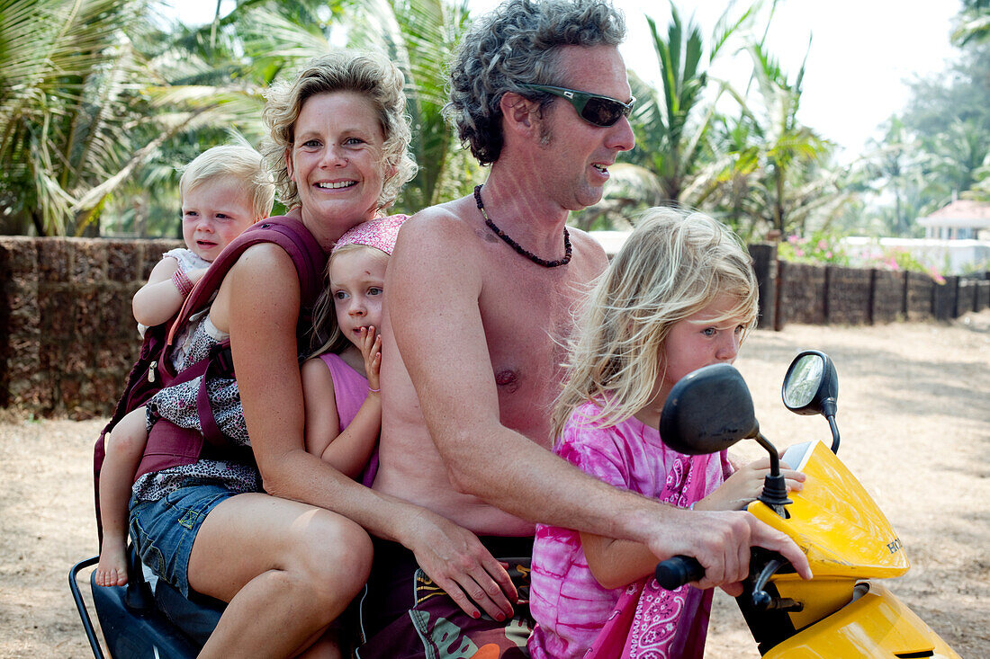 Die Familie Reynolds im Urlaub in Goa transportiert die Familie im indischen 5-up auf einem Moped, Turtle Beach, Goa, Indien.