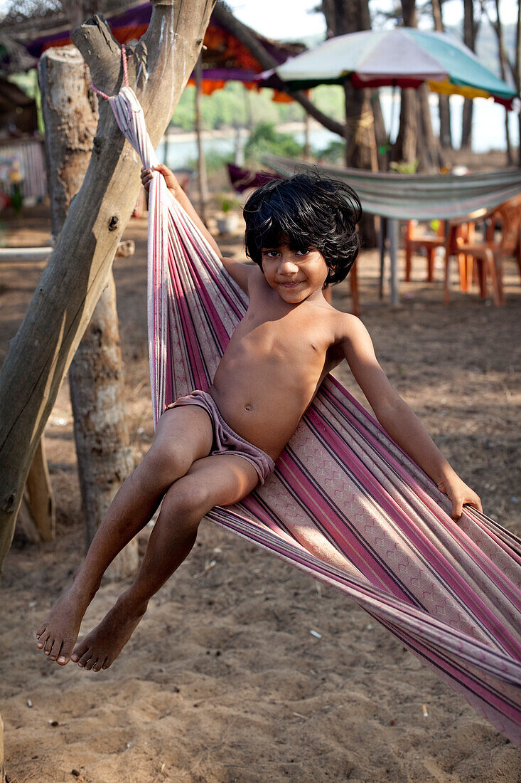 Ein einheimisches Kind in einer Hängematte am Turtle Beach, Goa, Indien.