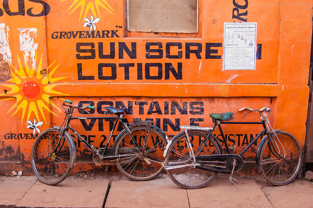 Indien,Karnataka,Zwei Fahrräder lehnen an der Wand und werben für Sonnenschutz,Gokarna