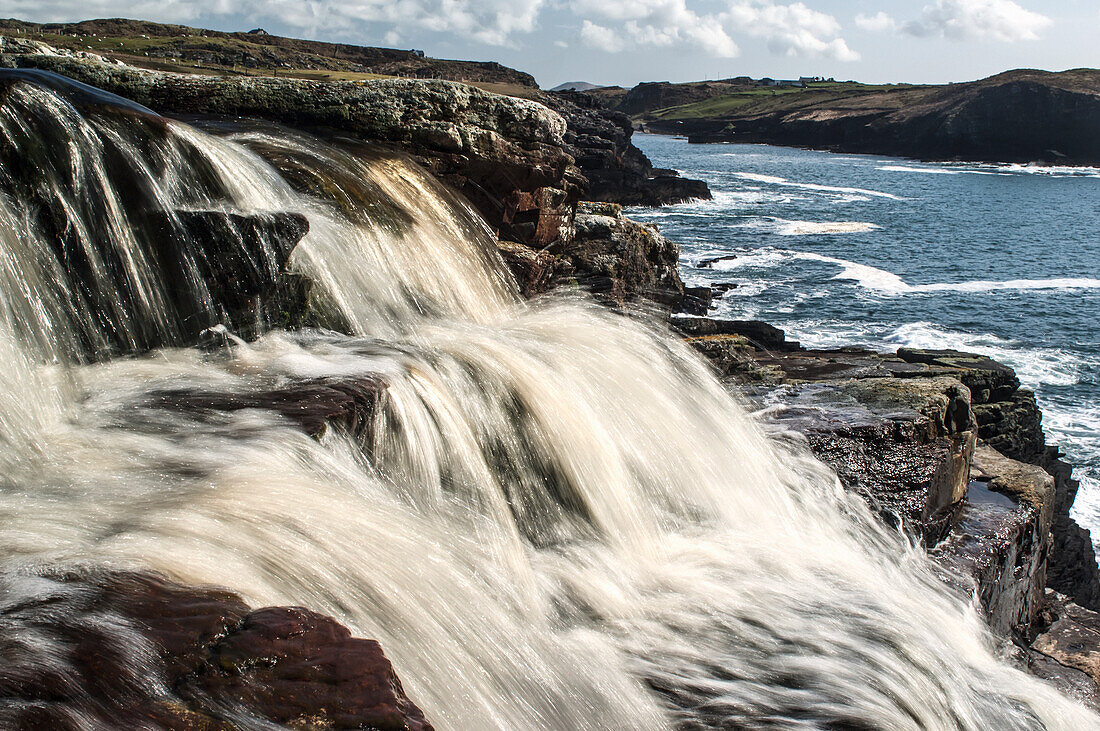 UK,Ireland,County Kerry,Cahersiveen,Peat colored water pouring into Cooncrome Harbor