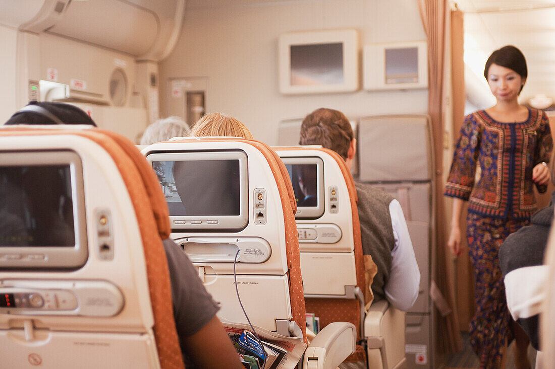 Passengers Seated Aboard An Airplane And A Flight Attendant In The Aisle,Singapore