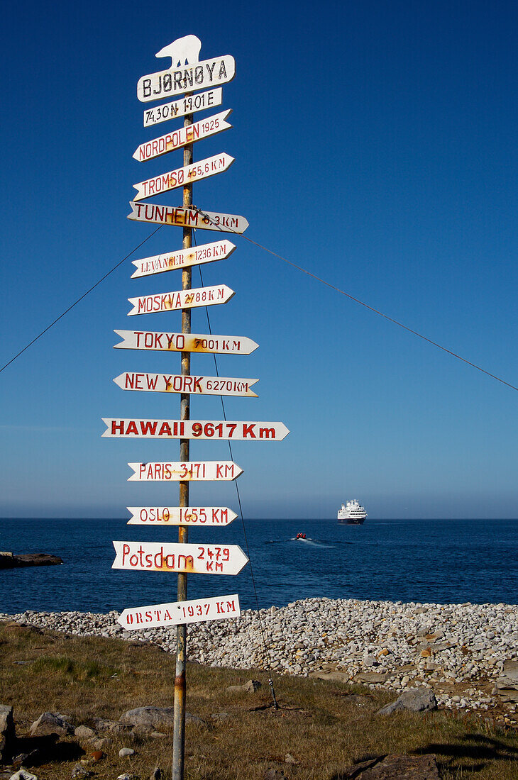 Schild an der Bäreninsel, mit Kreuzfahrtschiff in der Ferne, Svalbard, Norwegen