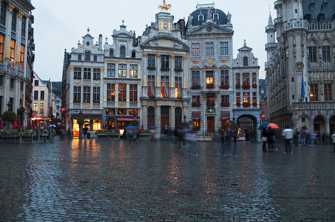 Fußgänger, die über einen nassen Stadtplatz gehen, Brüssel, Belgien