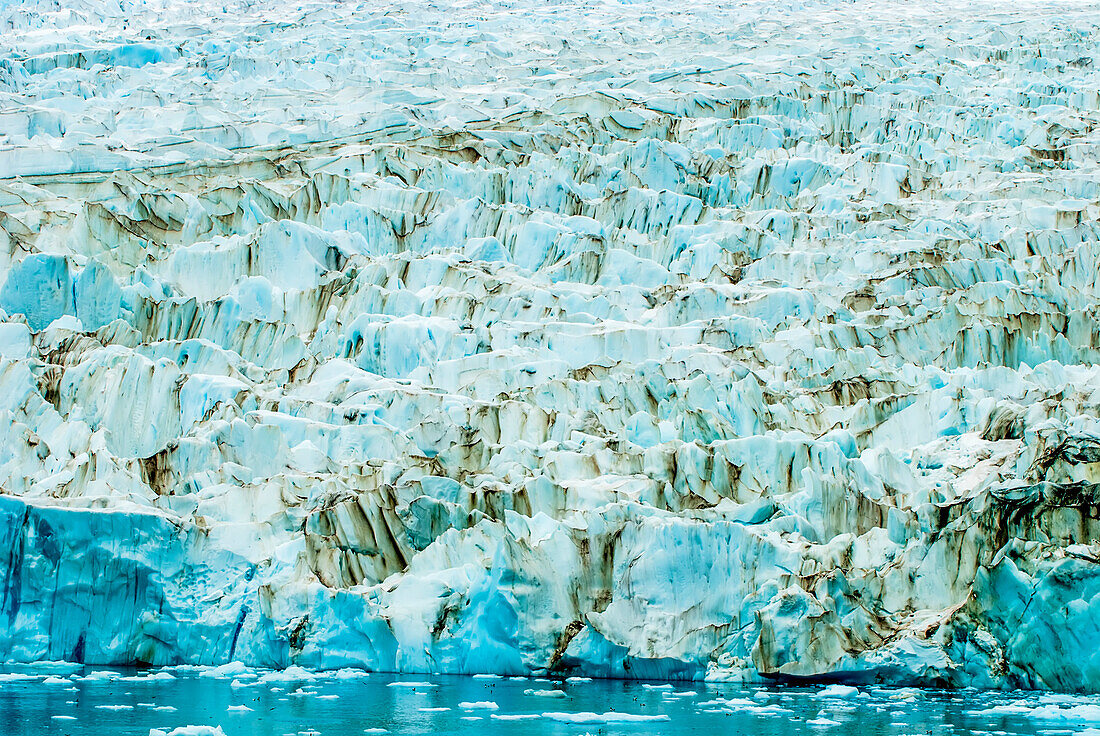 Linien und Muster eines Eisbergs mit blauem Eis, das sich im Wasser spiegelt, Antarktis