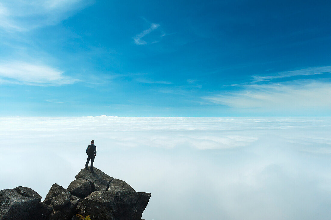 Ein Wanderer bewundert die Aussicht von der Spitze von Sgurr Nan Eag, einem der Gipfel der Black Cuillin, Isle Of Skye, Schottland