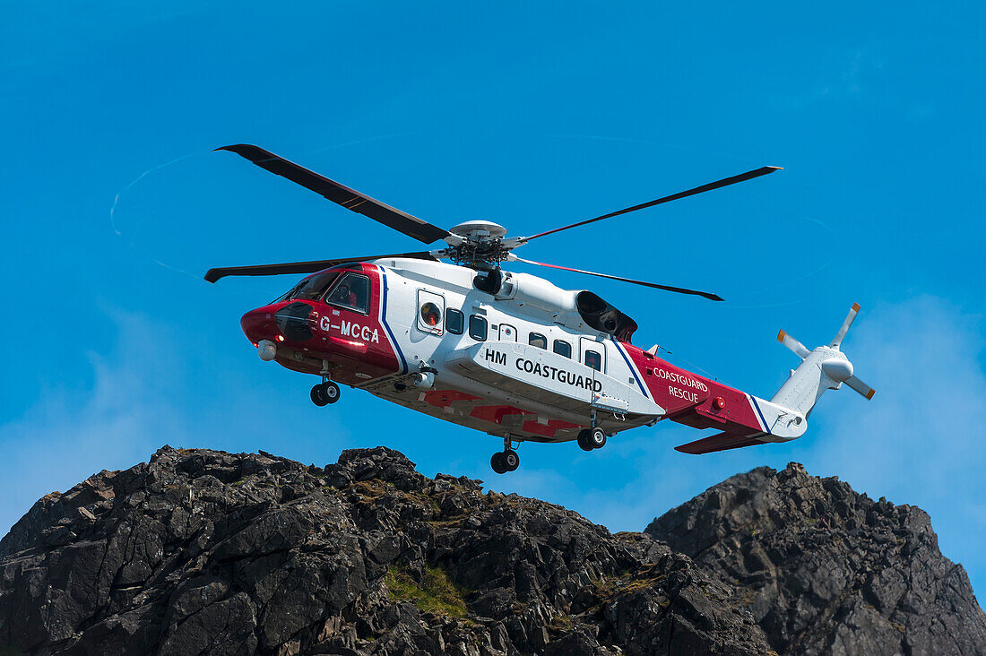 Rettungshubschrauber der Küstenwache schwebt über dem Bergkamm der Black Cuillin, Isle Of Skye, Schottland