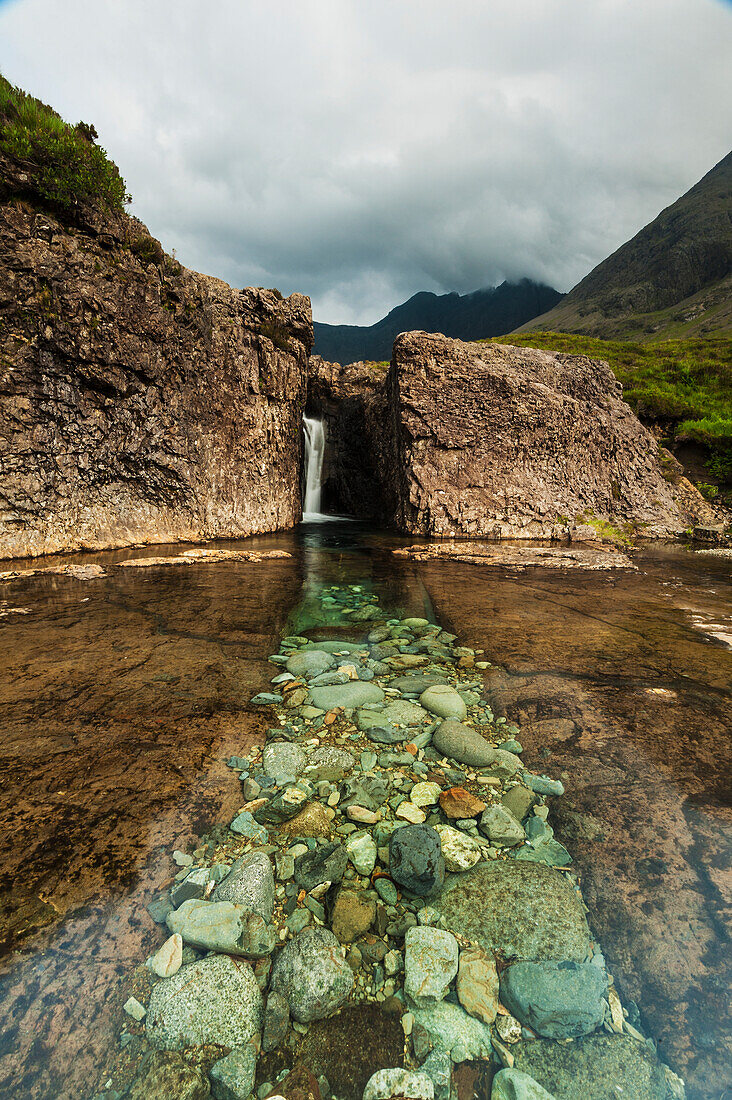 Eine Reihe blasser Felsen, die zum Wasserfall in Coire Na Creiche (The Fairy Pools) in der Nähe von Glen Brittle führen, Isle Of Skye, Schottland