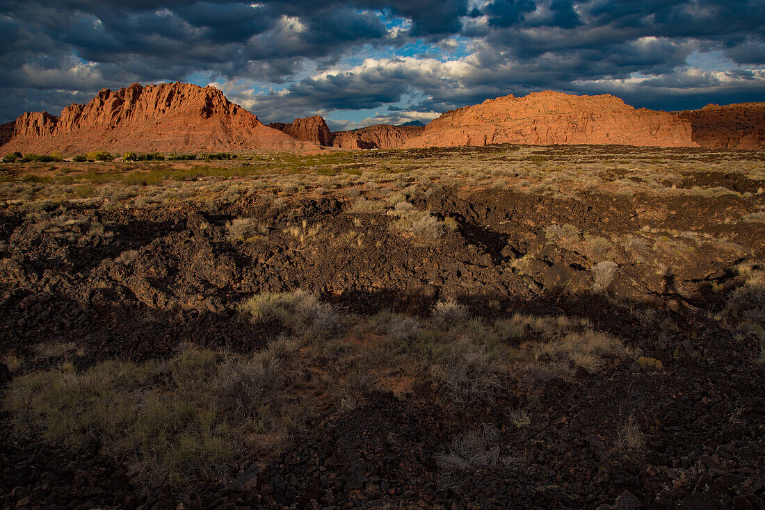 Hiking trail through Snow Canyon,behind the Red Mountain Spa,with Snow Canyon Mountain Range in the background at Red Cliffs Desert Reserve around St George Town with red cliffs and dark clouds in a blue sky,St George,Utah,United States of America