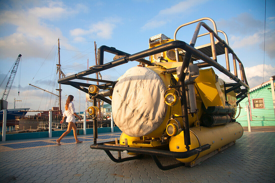 Junge Frau geht an einem historischen Tiefsee-Forschungs-U-Boot vorbei, das am Hafen von George Town, Grand Cayman, Cayman Islands, Karibik, ausgestellt ist