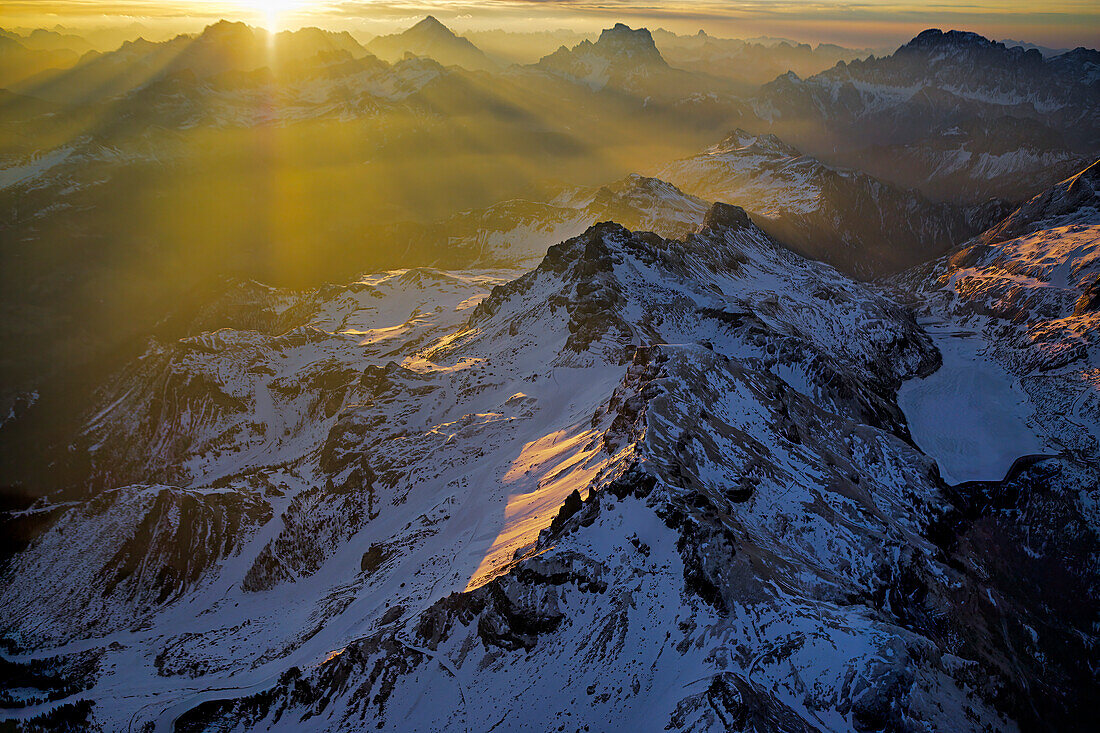 Early morning rays of sunlight peek over jagged peaks in the Dolomite Mountains,a mountain range in the northern Italian Alps,Italy