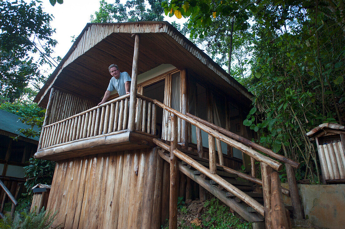 Man stands on the porch of his cabin looking down at the camera,near Bwindi Impenetrable Forest National Park in Uganda,Uganda