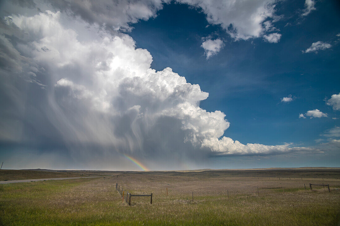 Riesige Gewitterwolke, die Regen und Hagel auf die Prärie von Südost-Wyoming schüttet und einen wunderbaren Regenbogen für diejenigen bietet, die auf dieser Seite des Sturms sind, Chugwater, Wyoming, Vereinigte Staaten von Amerika