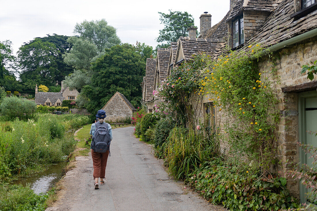 Woman walks down a paved lane beside houses in the UK,United Kingdom