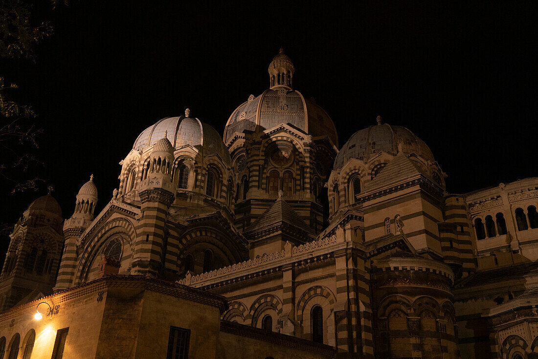 Kuppeln der historischen Kathedrale von Marseille bei Nacht, mit einer Straßenlaterne, die hell in der Dunkelheit leuchtet, Marseille, Frankreich