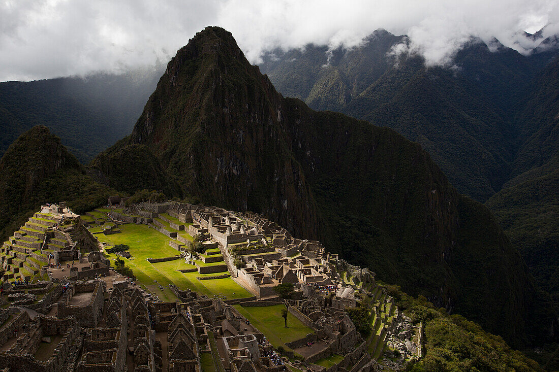 Sonnenlicht fällt durch eine Wolkenlücke auf Machu Picchu, Peru