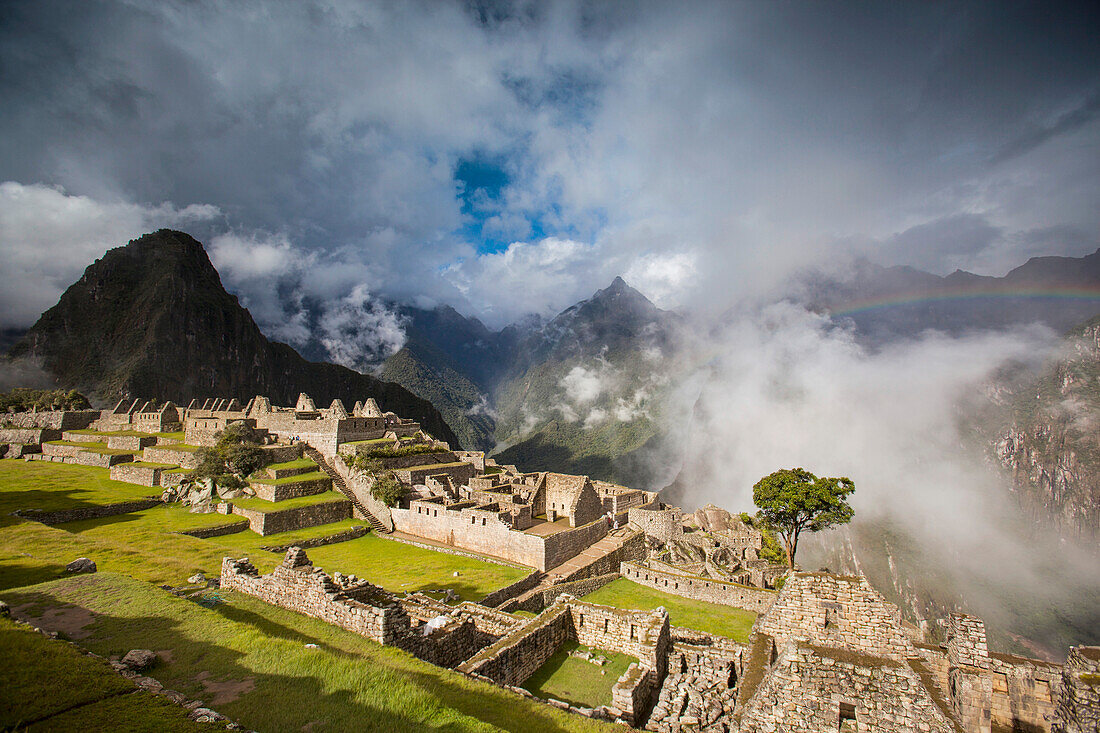Regenbogen taucht aus den Wolken über Machu Picchu, Peru