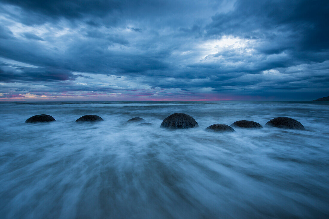 Waves moves around Moeraki Boulders along a stretch of Koekohe Beach on the South Island of New Zealand,Hampden,North Otago,New Zealand