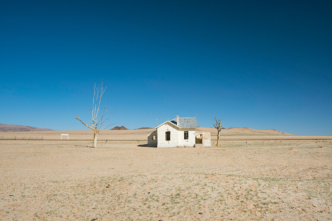 Verfallenes Haus in der Nähe einer Eisenbahnlinie, die durch die Wüste führt, Namibia