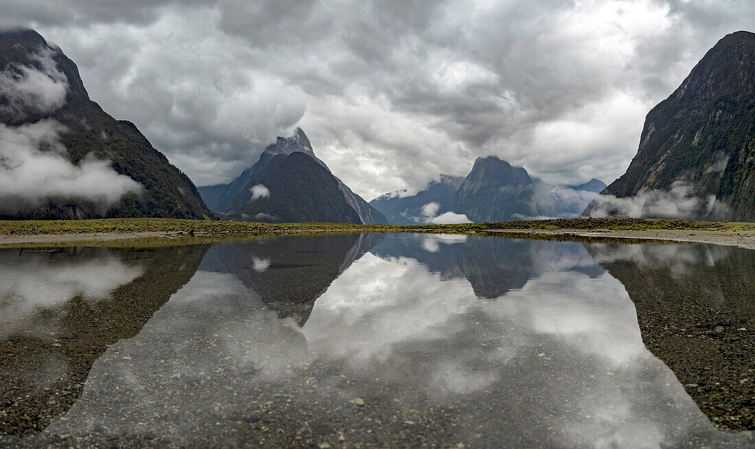 Stürmische Morgenwolken und Mitre Peak spiegeln sich im Milford Sound, Milford Sound, Südinsel, Neuseeland