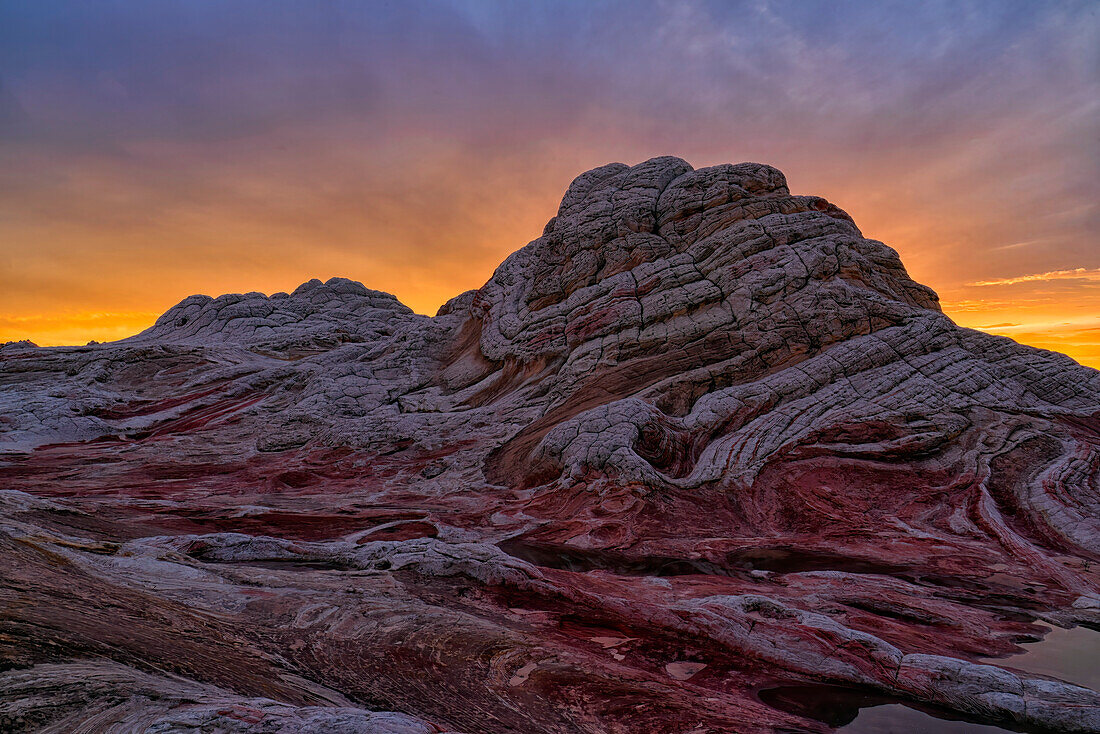 Sonnenuntergang über dem wundersamen Gebiet, das als White Pocket in Arizona bekannt ist. Es ist eine fremde Landschaft mit erstaunlichen Linien, Konturen und Formen. Hier erzeugt die untergehende Sonne wunderschöne Farben am Himmel über dem Gebiet, Arizona, Vereinigte Staaten von Amerika