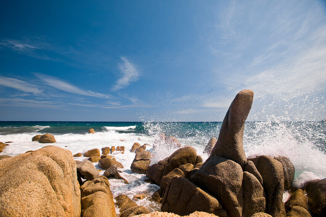 Blaues Wasser plätschert gegen Felsen am Strand an der Cote d'Azure, Französische Riviera, Frankreich