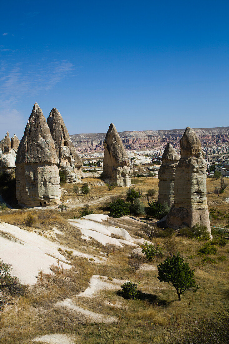 Cave Houses carved into the volcanic rock formations called Fairy Chimneys,against a bright blue sky near the town of Goreme in Pigeon Valley,Cappadocia Region,Nevsehir Province,Turkey