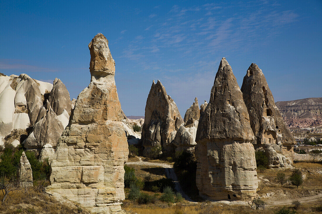 Cave Houses carved into the volcanic rock formations,Fairy Chimneys,against a bright blue sky near the town of Goreme in Pigeon Valley,Cappadocia Region,Nevsehir Province,Turkey