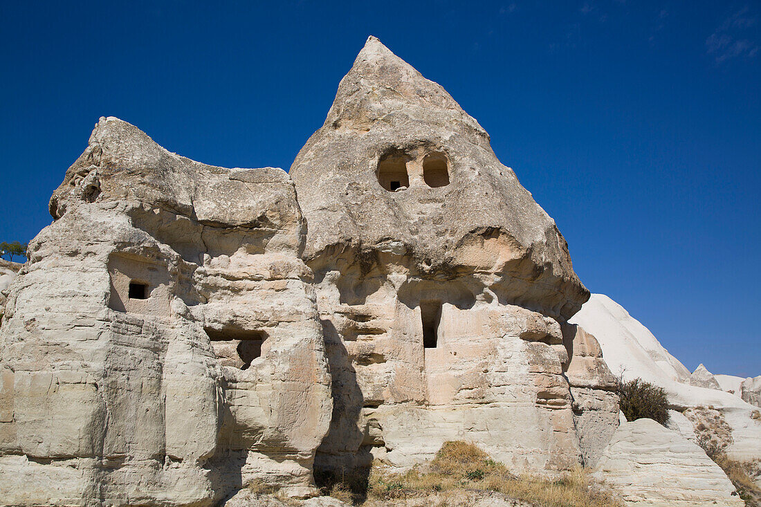 Close-up of a rock house carved into the volcanic rock formations,a Fairy Chimney,against a bright blue sky near the Town of Goreme in Pigeon Valley,Cappadocia Region,Nevsehir Province,Turkey