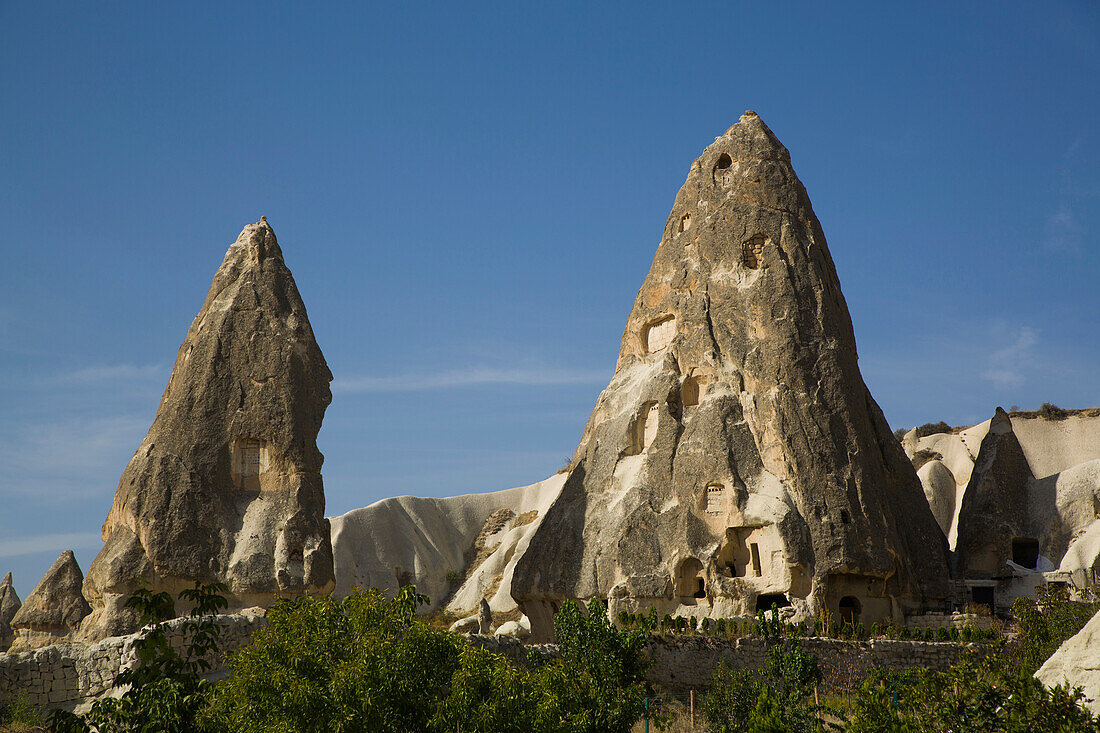 Höhlenhäuser in Felsformationen vor einem strahlend blauen Himmel in der Nähe der Stadt Goreme im Pigeon Valley, Region Kappadokien, Provinz Nevsehir, Türkei