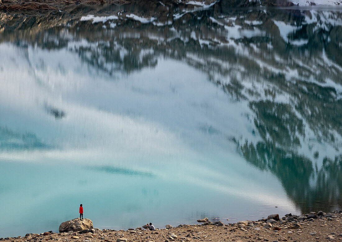 Person stands looking at the reflection in Laguna De los Tres to the foot of Mount Fitz Roy,in Los Glaciares National Park,El Chalten, Argentina