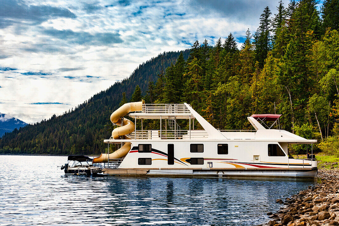 Ein Hausboot, geparkt an einer Anlegestelle am Ufer des Shuswap Lake, Shuswap Lake, British Columbia, Kanada