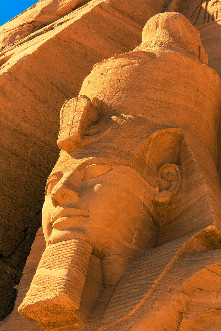 Nahaufnahme des Kopfes einer der in den Berghang gehauenen Statuen von Ramses II. vor dem Großen Sonnentempel von Abu Simbel, Abu Simbel, Nubien, Ägypten
