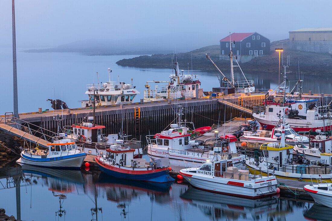 A late night foggy viewpoint of the harbour and fishing docks at Djupivogur,Eastern Iceland where there is still light late in the night when summer soltice is approaching,Djupivogur,Iceland