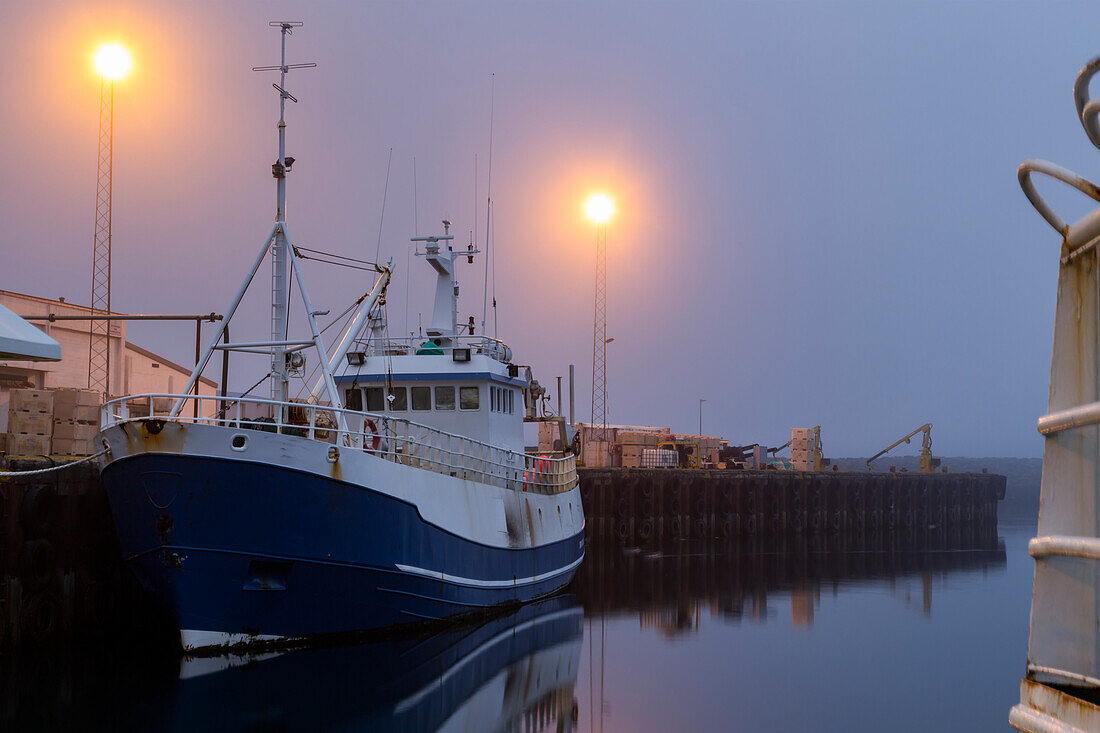 A fishing vessel sits idle in the late night fog at the docks of Djupivogur village,Eastern Iceland in summer solstice,Djupivogur,Iceland
