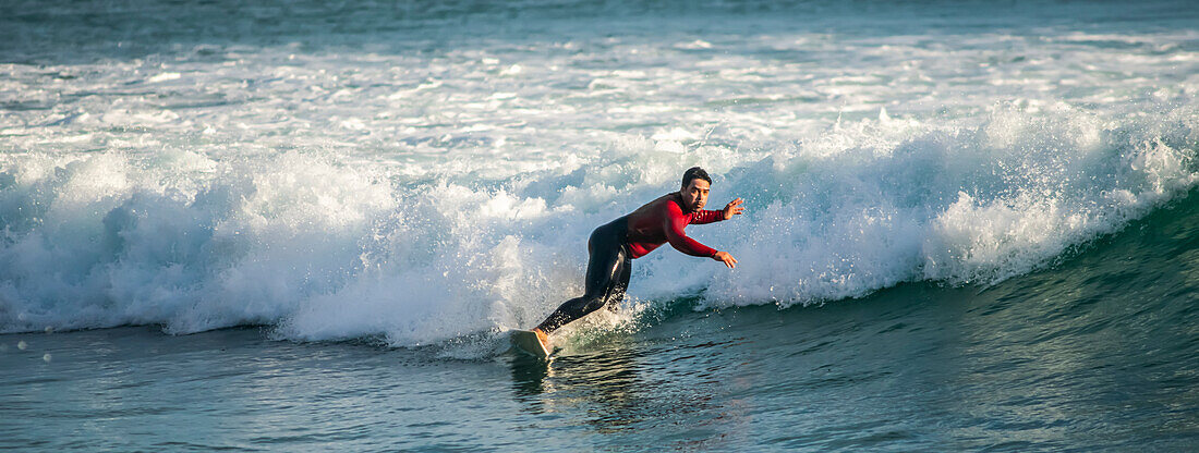 Surfen in der Abenddämmerung in der Houghton Bay, Wellington, Neuseeland