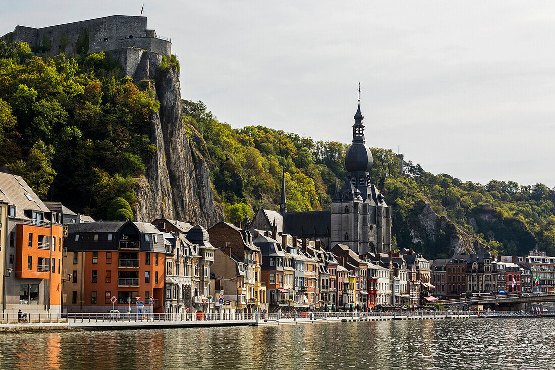 City of Dinant along the River Meuse with a large church steeple and high cliffs with a stone fortress on top,Dinant,Belgium