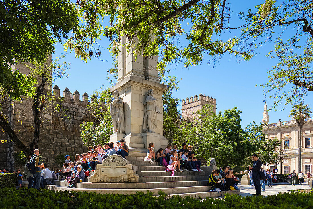 School children having a lunch break,monument to the Immaculate Conception,Plaza del Triunfo,Real Alcazar in background,Seville,Andalusia,Spain